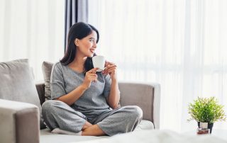 Young asian woman drinking coffee on a sofa bed at home
